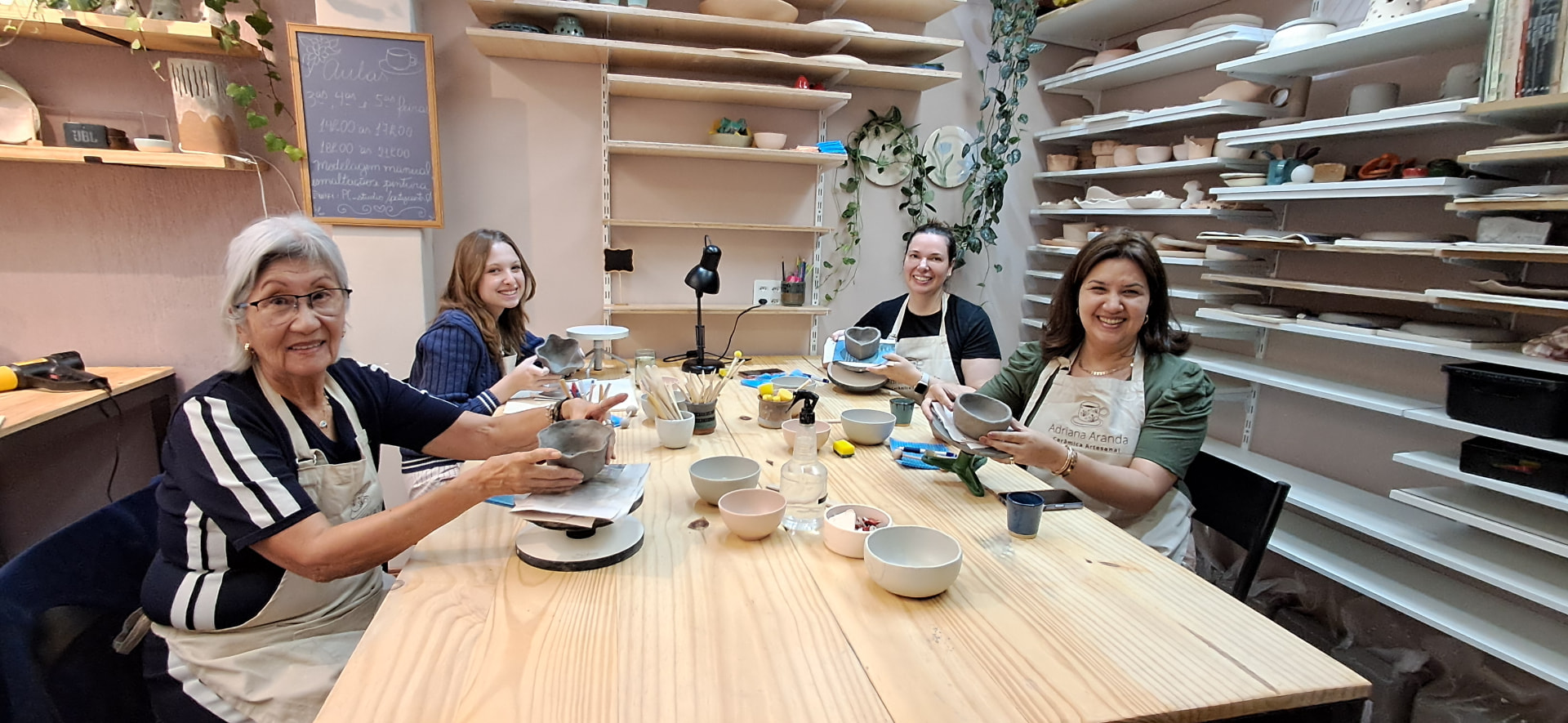 Turma de alunas modelando em volta da mesa do ateliê